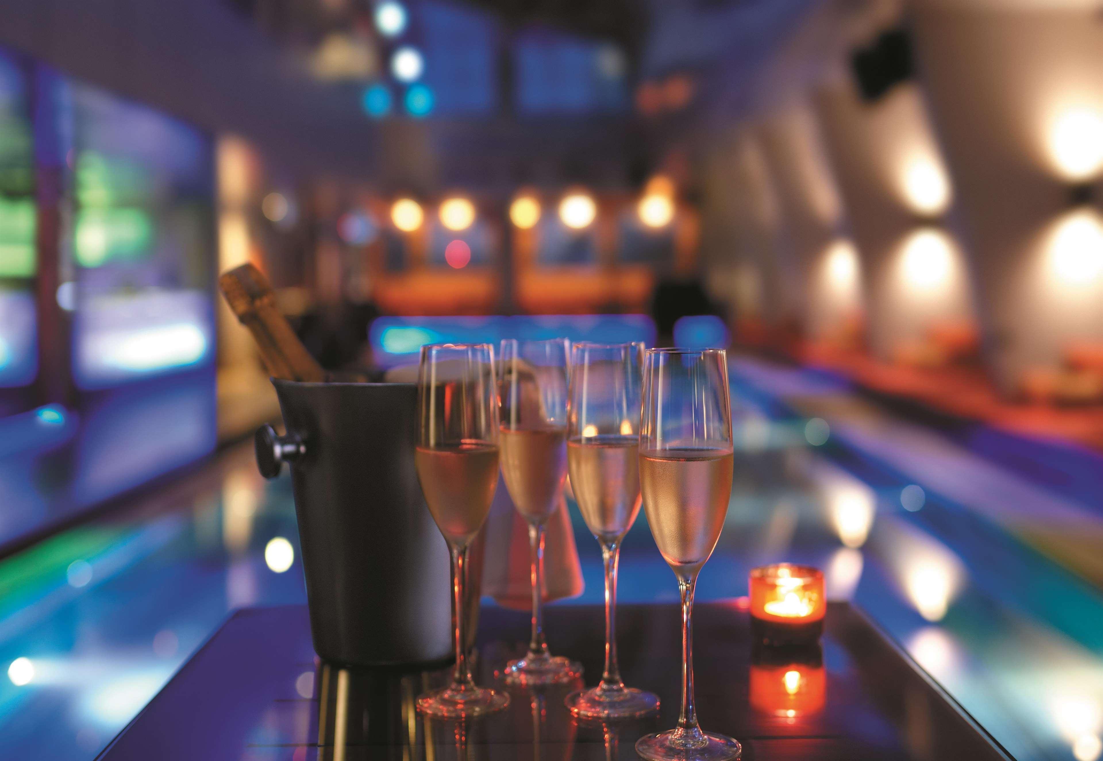 Traders Hotel, קואלה לומפור מראה חיצוני תמונה The photo depicts a luxurious setting, likely in a bar or lounge. There are several champagne flutes filled with sparkling wine arranged neatly on a table. To the left, there is a bucket, possibly containing ice and a bottle of champagne. The backgro
