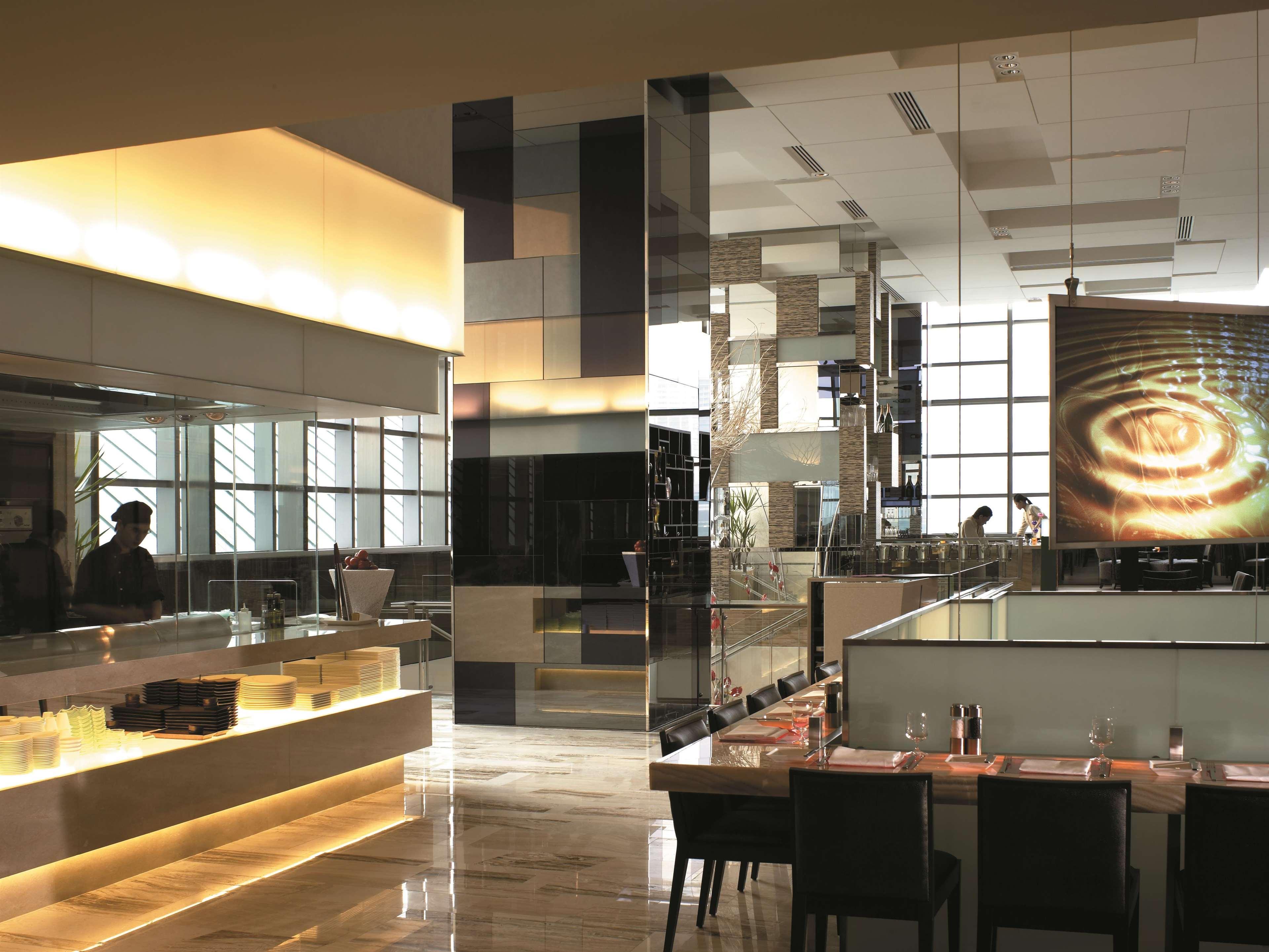 Traders Hotel, קואלה לומפור מראה חיצוני תמונה The photo shows a modern restaurant interior. It features a sleek design with glossy surfaces and warm lighting. The space includes a counter area with a well-lit service section, and a dining area with dark wooden tables and chairs. Large windows al